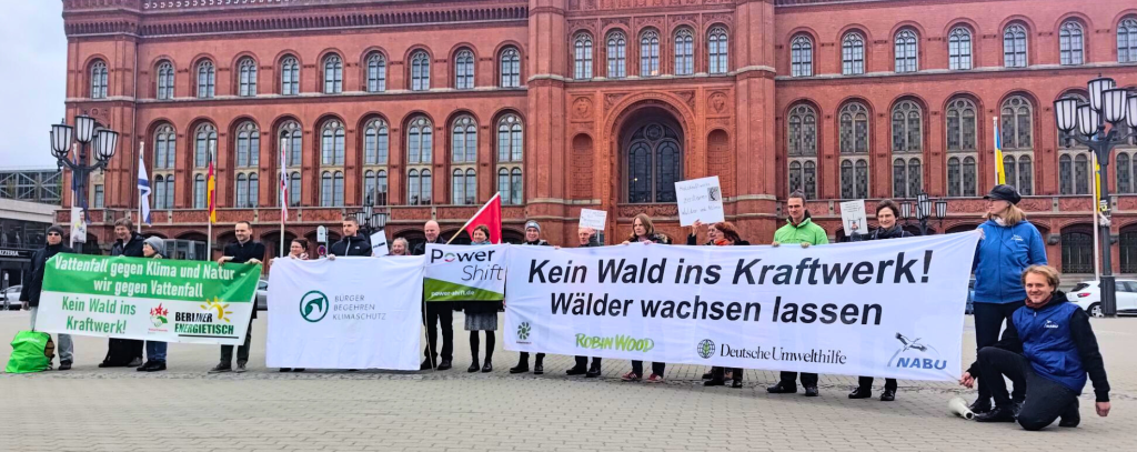 Viele Menschen vor einem alten, roten Backsteingebäude mit einigen bannern.